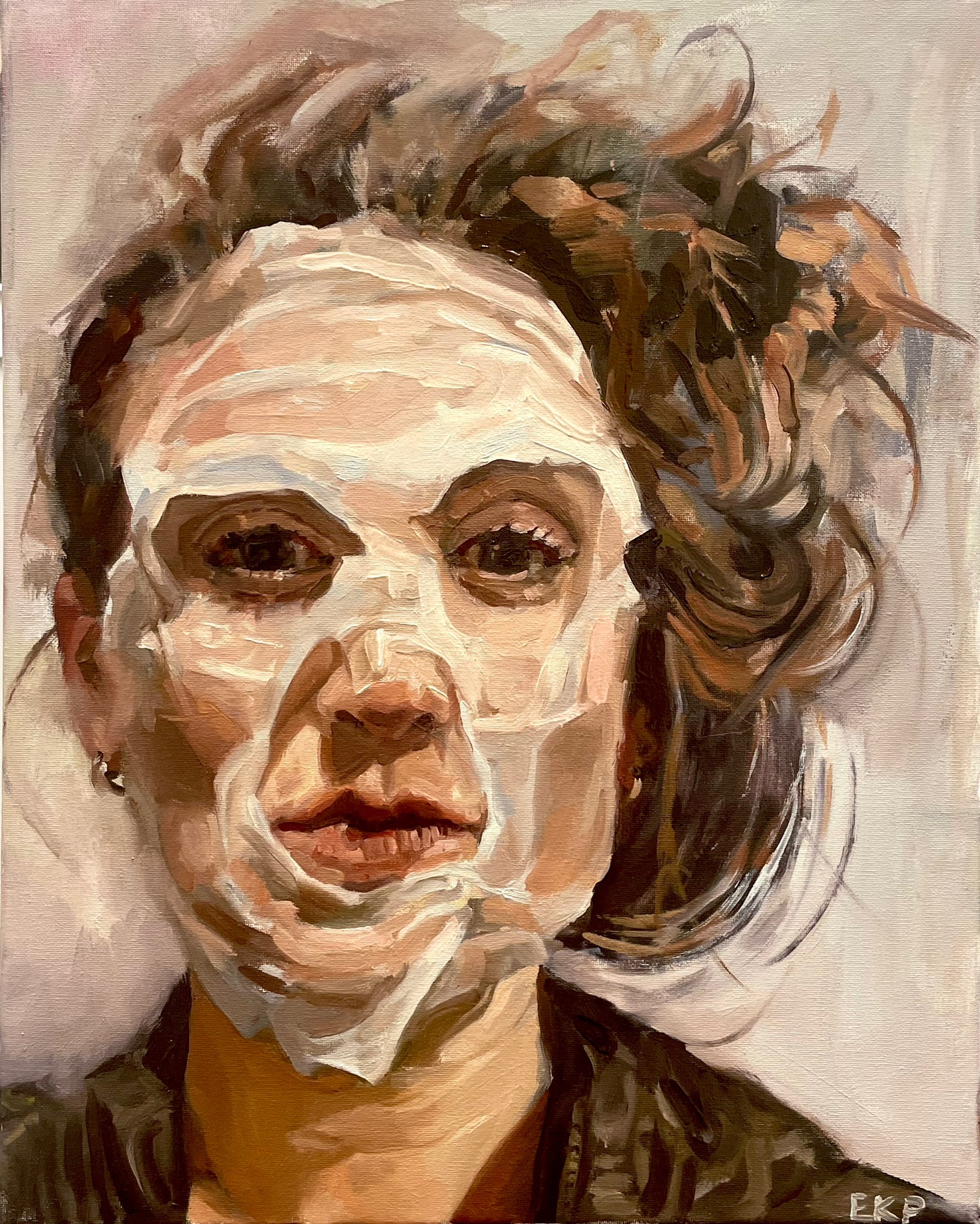 Portrait of a person with a white facial mask, dark eyes, and messy bun.